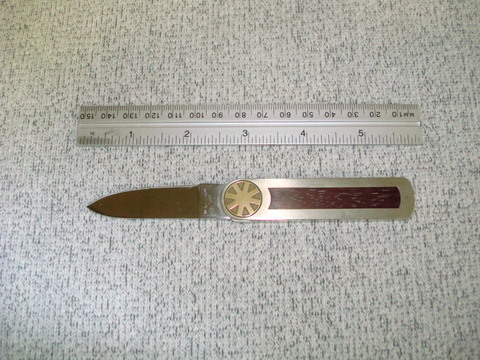 This Kershaw knife has a small pin in a miniature rack and pinion built into the pivot.  The small round coin at the pivot is used to open the blade where it locks.  To unlock the knife, turn the coin back towards closed. the rack drives the pin under the lock and releases it. Simply continue to turn the coin and the blade closes.