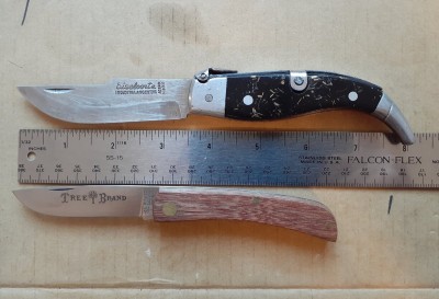 The Biselcorte Navaja above and a sodbuster pattern by Boker Arbolito below. The biselcorte has a stainless blade and black plastic scales with gold colored flecks embedded in them.