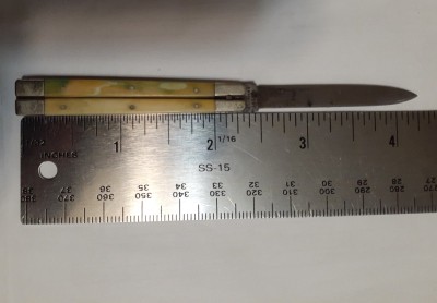 In the fully open position, carbon steel blade, nickel silver bolsters and liners, and ivory scales. This is a tiny knife.